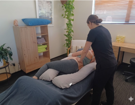 A professional therapist provides a specialized pregnancy massage, using a side-lying position and supportive cushioning to ensure maximum comfort and safety while relieving maternal back and hip tension.